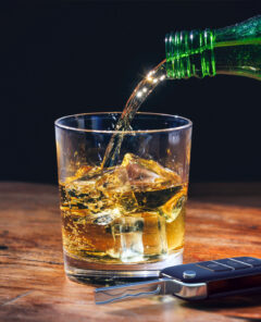 Drinking and driving concept. Car key and whiskey  glass and bottle on a wooden bar counter background. 3d illustration.