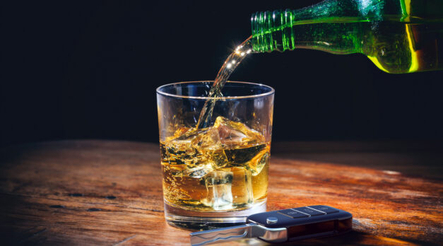 Drinking and driving concept. Car key and whiskey  glass and bottle on a wooden bar counter background. 3d illustration.